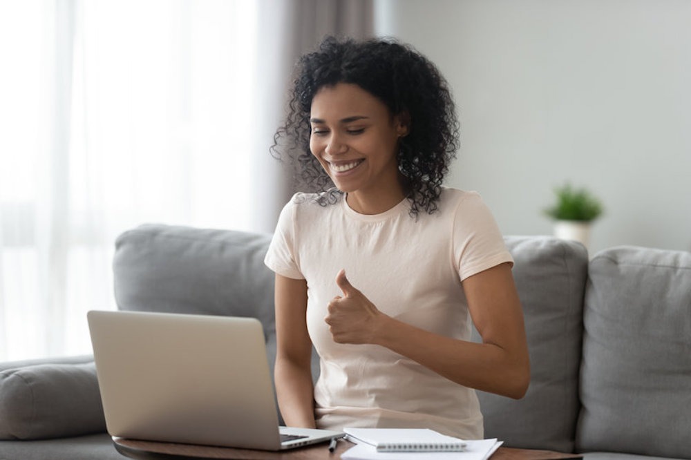Smiling African American woman showing thumbs up, using laptop Online On-Demand Video Tai Chi and Qigong Classes Student on Laptop
